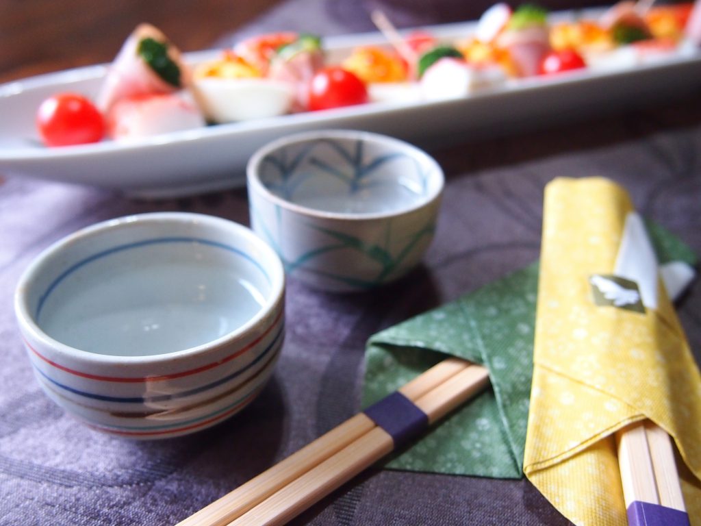 日本酒とカラフルな和食がテーブルに並んでいる