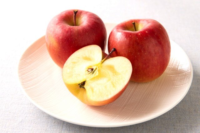 2個のリンゴとカットされたリンゴが皿にのっている。