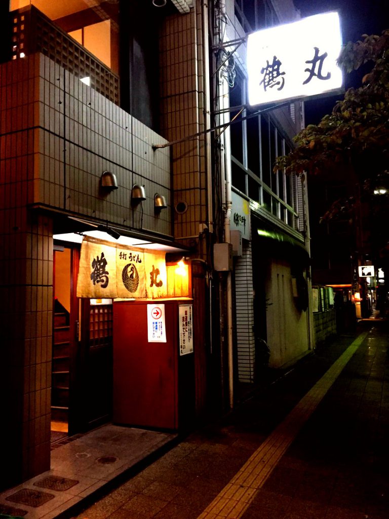 手打ちうどん店「鶴丸」の外観。看板と暖簾が目印。