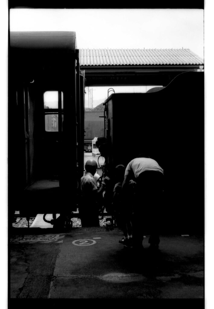汽車「D51895」と貨車の連結部分に入って作業をしている職員と見守る父と子