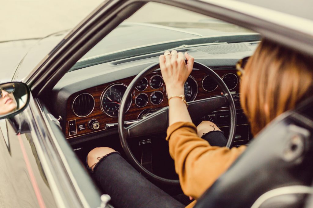 女性が車のハンドルを握って運転している。