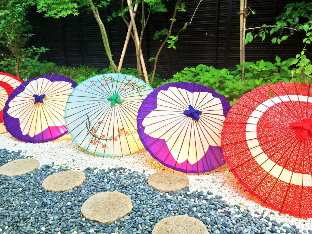 カラフルで様々な模様の和傘が横一列に並んでいる様子。