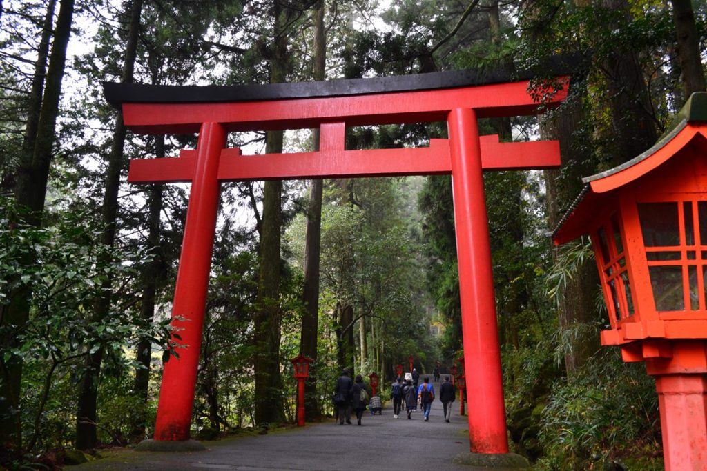 箱根神社の大きな赤い鳥居の下を通る人々。