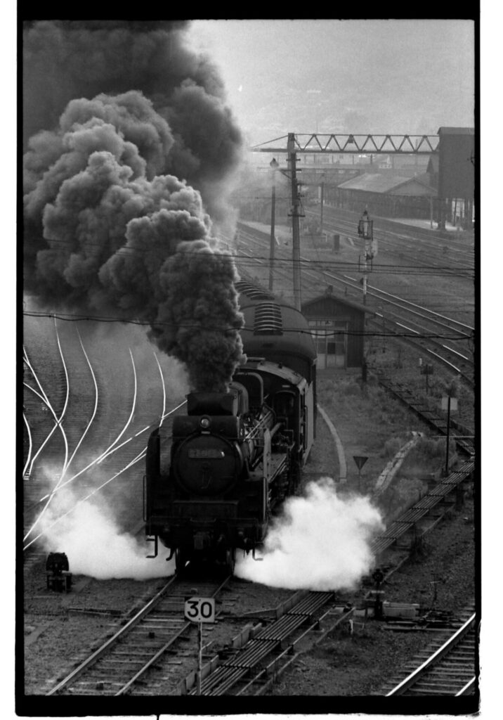 黒煙を上げて走る汽車の白黒写真