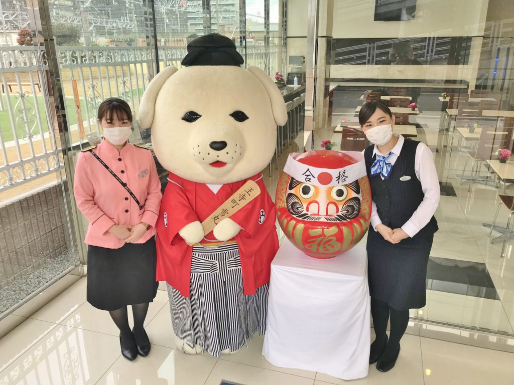 王寺町のご当地キャラクターの「雪丸」と駅員の女性2人がこちらを向いている。