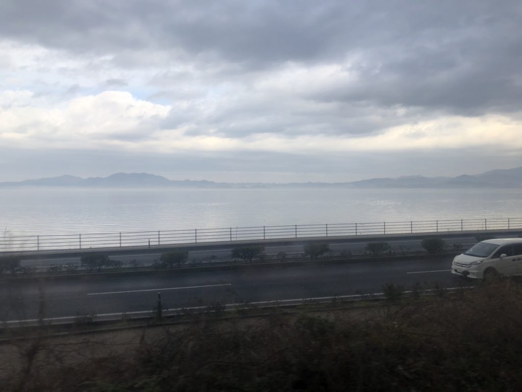 サンライズ出雲の車窓から見える宍道湖。曇っているが湖の向こうには島が見える。