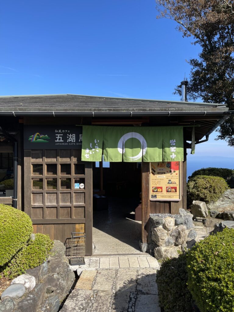和風カフェ「五湖庵」外観。木造の平屋。入り口には黄緑色の暖簾がかかっており、右側にはメニューの看板があります。