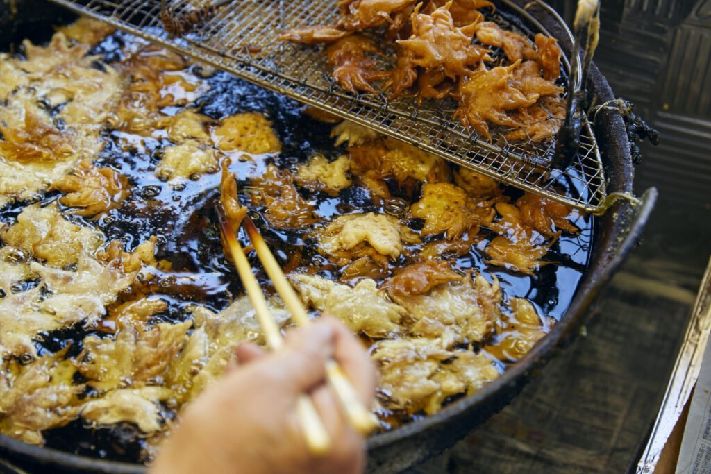 もみじの葉を一枚ずつ箸でつまんで、油で揚げて天ぷらを作っている様子。