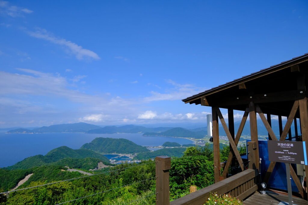 天空の足湯。右側にウッドデッキのテラスと、左側に若狭湾と三方五湖が見えます。