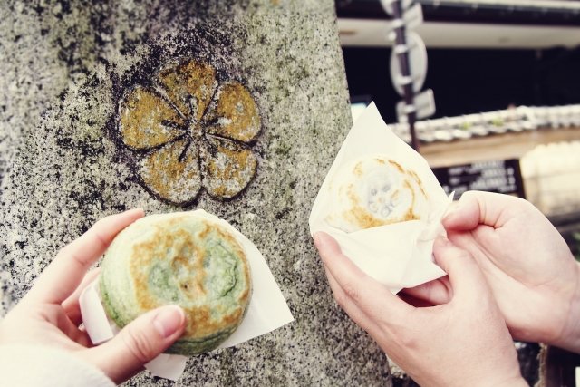 梅ヶ枝餅を手に持っている。