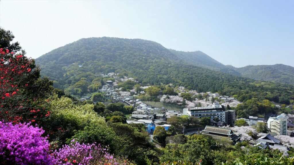 緑の山の麓には町が見え、所々桜が咲いている。鮮やかなピンクや赤色の花も咲いている。