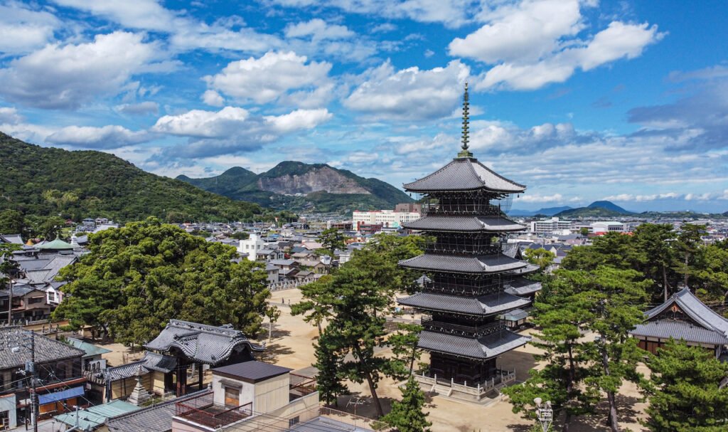 晴れた空の下、鎮座する五重塔。周辺の歴史的建造物や、遠くの町並み、山々まで見える。