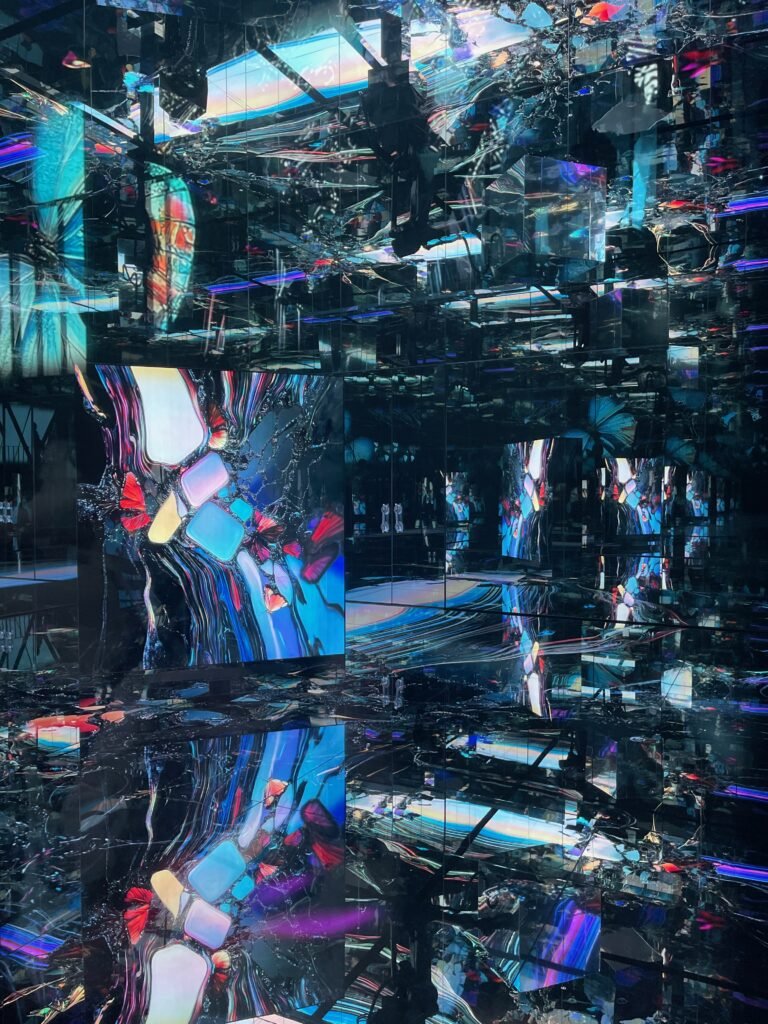 大阪・関西万博の落合陽一プロデュース「null²（ヌルヌル）」パビリオンの内部。青白い光の中、湾曲した鏡面壁が無限の合わせ鏡を作り出し、LEDの床と来場者の影がどこまでも続く幻想的な没入空間。