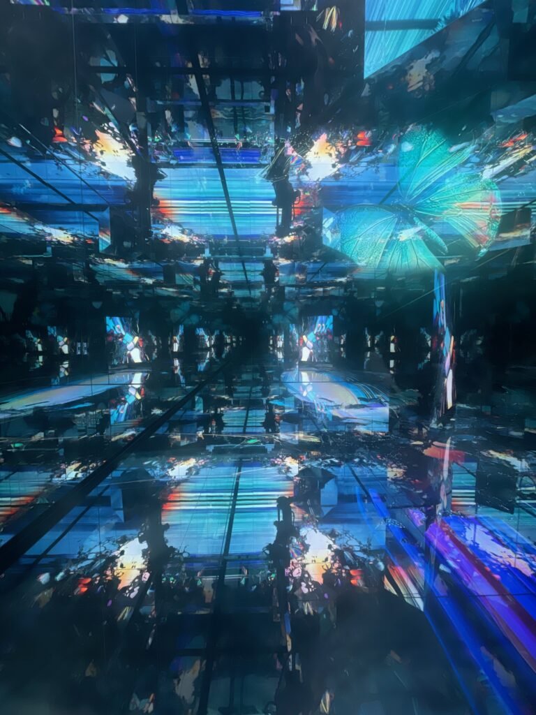 大阪・関西万博「null²」内部の全景。床から天井まで続く巨大な湾曲ミラー膜が空間を包み込み、光の渦のような無限反射を生み出す。落合陽一氏が提唱する「計算機自然」の世界観を体現した瞬間。