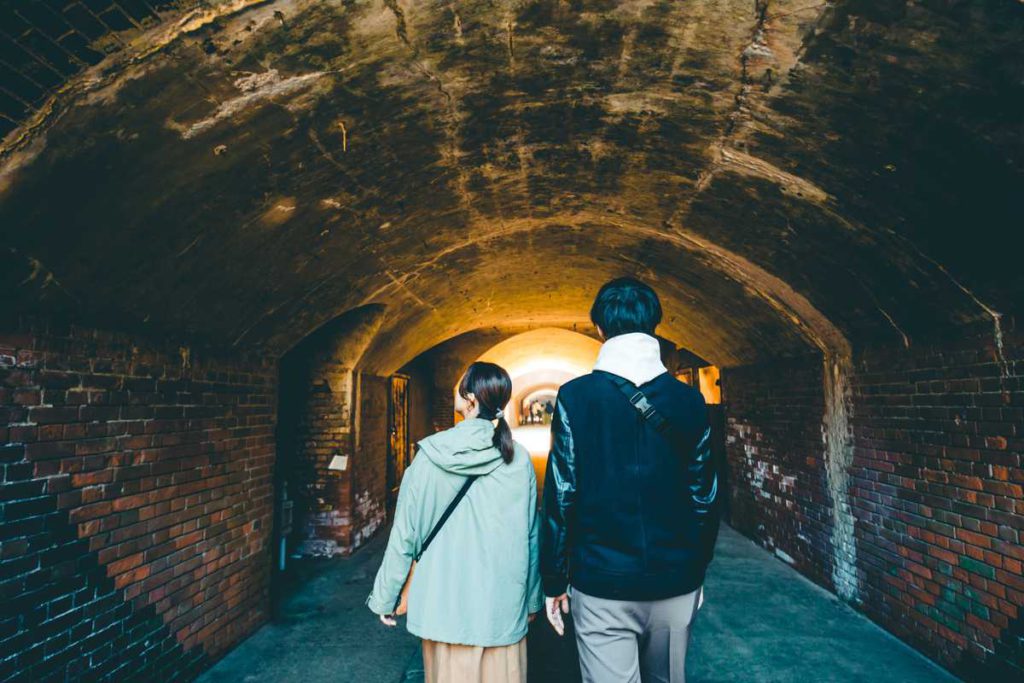 Couple walking through the brick tunnel at Chiyogasaki Battery Ruins