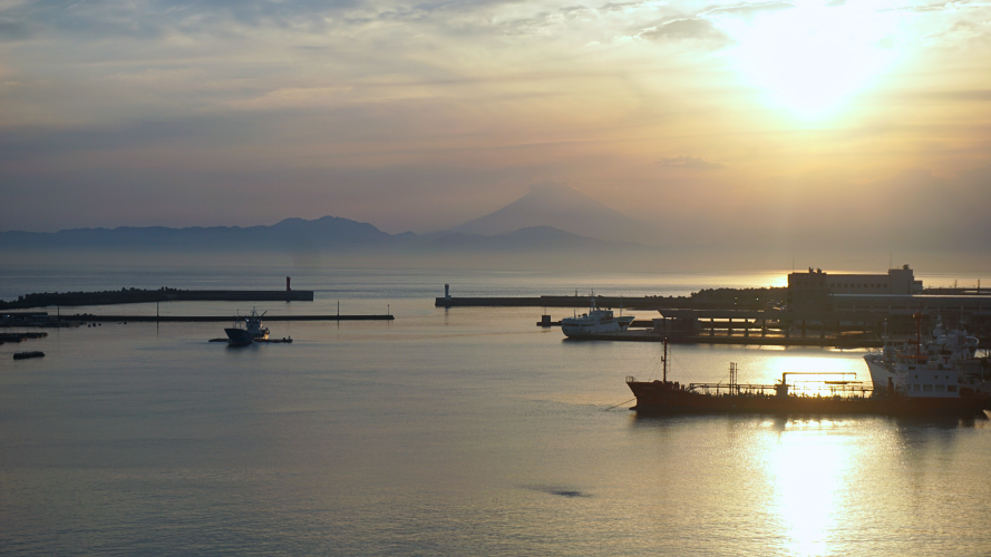 A photo of a port in Kanagawa Prefecture. The sun is rising, and Mount Fuji is in the background.